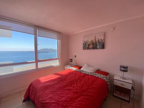 a bedroom with a red bed and a large window at Playa Herradura in Coquimbo