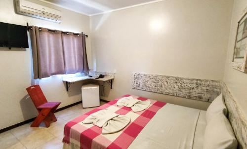 a bedroom with a bed with a red and white blanket at Pousada Vila Parnaíba in Parnaíba