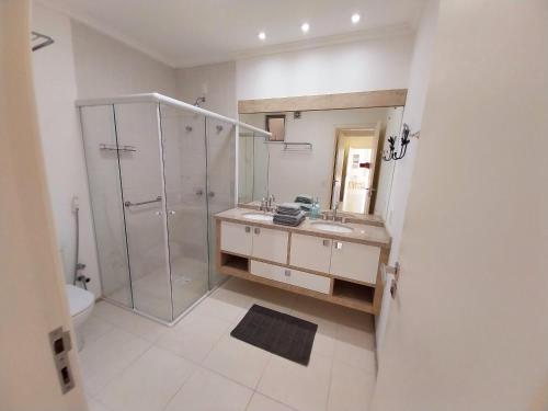 a bathroom with a shower and a sink and a mirror at Cobertura Frente Mar Campeche - 3 quartos, jacuzzi in Florianópolis