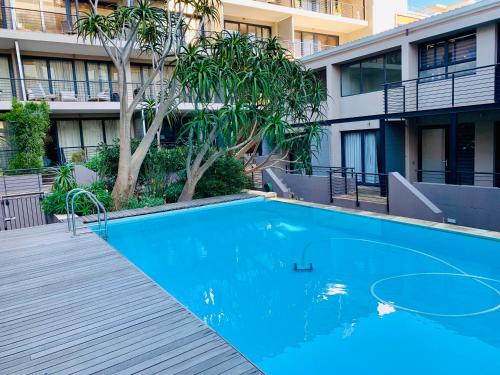 a blue swimming pool in front of a building at Avenue One Apartments in Cape Town