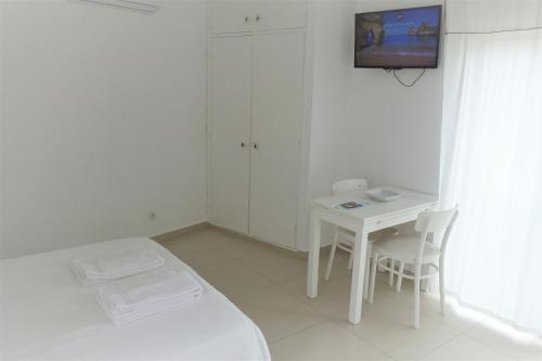 a white room with a bed and a table and a tv at Apartamentos Pinhão in Lagos