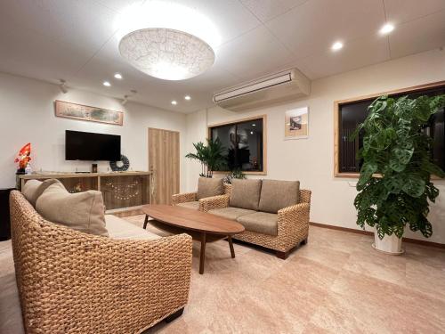 ein Wohnzimmer mit Stühlen, einem Tisch und einem TV in der Unterkunft 白浜の宿　 蘭 in Shirahama