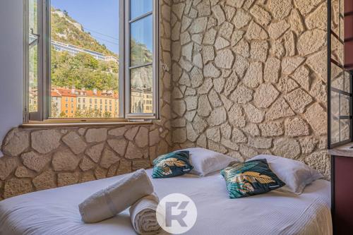 a bedroom with two beds and a stone wall at R'Apparts Studio Chic des Quais in Grenoble
