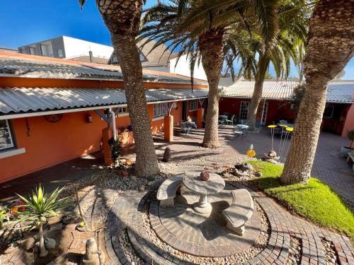 un patio con palmeras y una mesa en The Secret Garden Guesthouse en Swakopmund