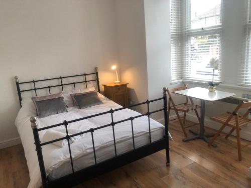 a bedroom with a bed and a table and a window at Self-contained Studio near Heathrow - 77VFR1 in Cranford