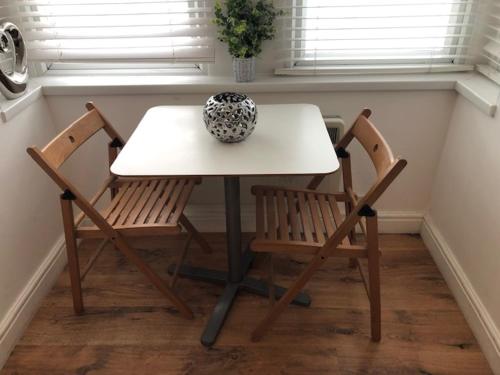 a table with two chairs and a vase on it at Self-contained Studio near Heathrow - 77VFR1 in Cranford