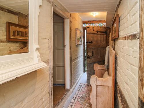 un pasillo de una casa con una puerta y una silla en Cobblers Cottage, en Whitchurch