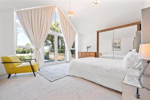 a white bedroom with a bed and a yellow chair at Hampshire gated home in exclusive location in Southampton