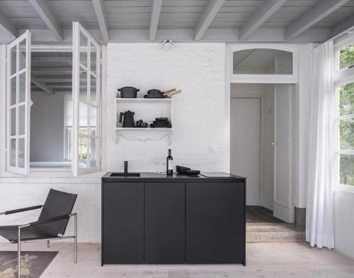 a black island in a white room with a chair at Het Witte Kasteel in Loon op Zand