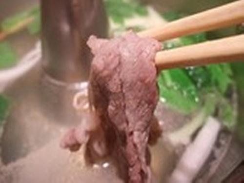a piece of meat on a pair of chopsticks at Yudanaka Tawaraya Ryokan in Yamanouchi