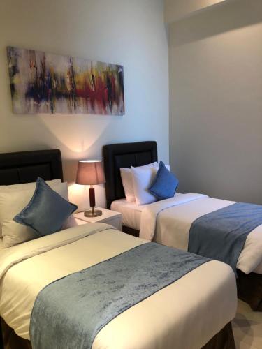 a bedroom with two beds and a painting on the wall at Boudl Al Jubail in Al Jubail