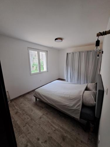een witte slaapkamer met een bed en een raam bij Superbe Rez-de-Jardin refait à neuf. in Breil-sur-Roya