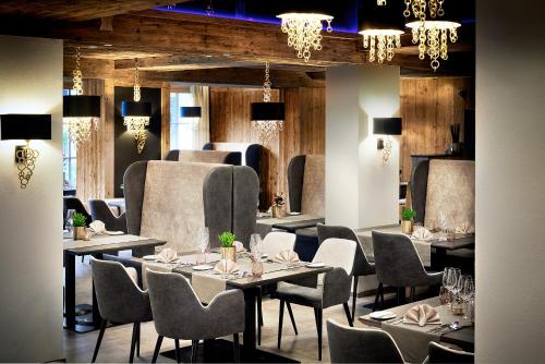 una sala da pranzo con tavoli, sedie e lampadari a braccio di Sporthotel Ellmau in Tirol a Ellmau