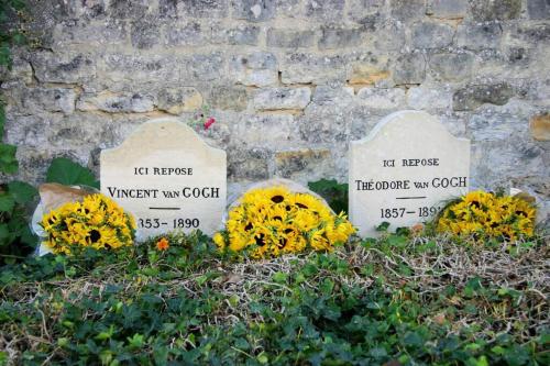 a grave with tombstones and flowers in front of a stone wall at Appartement cosy au coeur d'Auvers-Sur-Oise in Auvers-sur-Oise