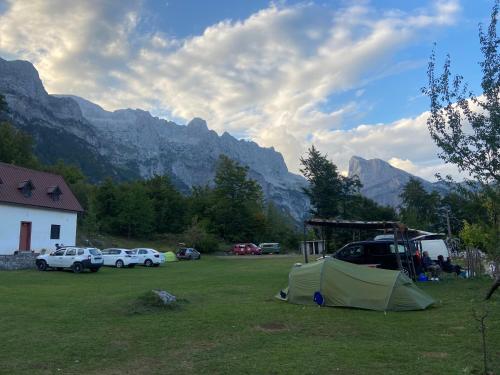a tent in a field with mountains in the background at Guesthouse Freskia in Theth