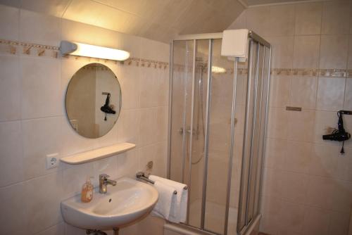 uma casa de banho com um lavatório e um chuveiro com um espelho. em Pension zur Schleuse am Elbe Lübeck - Kanal in Witzeeze em Witzeeze