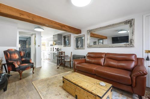 a living room with a leather couch and a table at Georgina in Lavenham