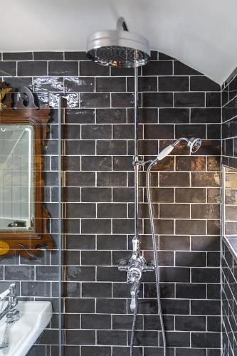 a shower in a bathroom with a black tiled wall at Georgina in Lavenham