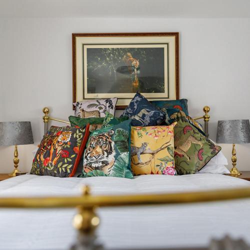 a bed with colorful pillows on it with two lamps at Georgina in Lavenham