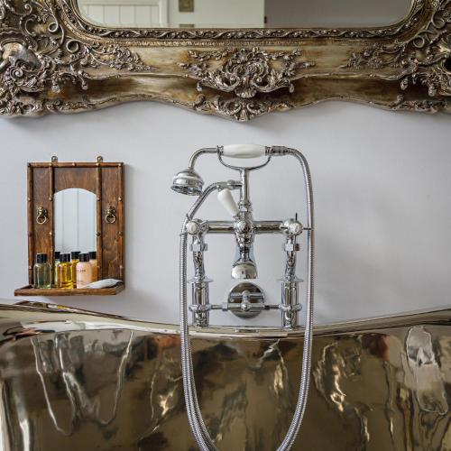 a mirror on the wall next to a bath tub at Georgina in Lavenham