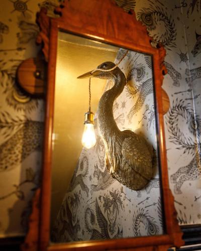 a clock with a duck on a wall with a light at Georgina in Lavenham