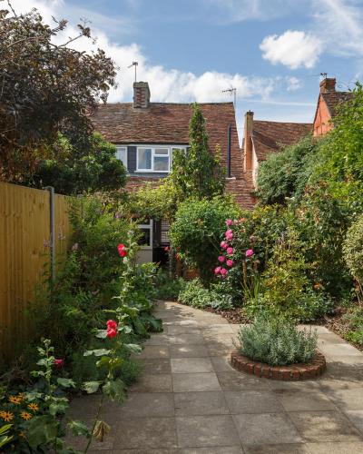 a garden with roses and plants in front of a house at Georgina in Lavenham