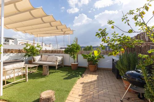 Tentudia Charming Apartments with Private Roof-Top or Patio in San Bernardo By Oui Seville في إشبيلية: فناء به عشب وأريكة ومظلة