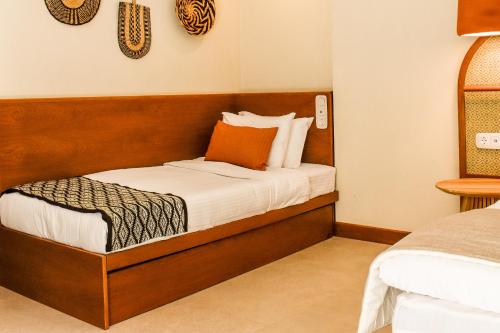 Schlafzimmer mit einem Bett mit orangefarbenem Kissen in der Unterkunft Mandraki Village Boutique Hotel in Koukounaries