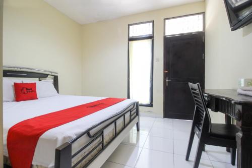 Schlafzimmer mit einem Bett und einem Schreibtisch mit einem roten Kissen in der Unterkunft RedDoorz near Puskesmas Sei Jang Tanjung Pinang in Tanjung Pinang 