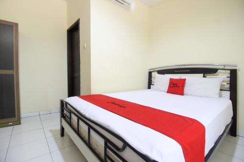 - une chambre avec un lit et une couverture rouge dans l'établissement RedDoorz near Puskesmas Sei Jang Tanjung Pinang, à Tanjung Pinang