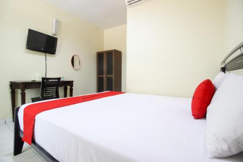 Schlafzimmer mit einem roten und weißen Bett und einem Schreibtisch in der Unterkunft RedDoorz near Puskesmas Sei Jang Tanjung Pinang in Tanjung Pinang 