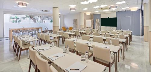 a conference room with tables and chairs and a screen at URH Sitges Playa in Sitges