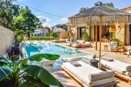 una imagen de una piscina con sillas y una villa en Mandraki Village Boutique Hotel, en Koukounaries