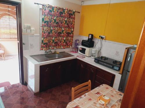 a kitchen with a sink and a microwave and a table at Fleurvilla in Pereybere