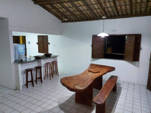 a kitchen with a wooden table and some bar stools at Sítio no Litoral Norte para curtir! in Subaúma