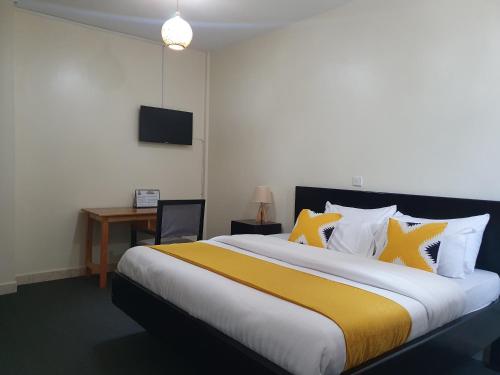 een slaapkamer met een groot bed met gele en witte kussens bij The Palm Residence in Kampala