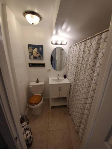 a bathroom with a toilet and a sink and a mirror at Beachy Bay Breeze Bungalow 2BR with parking and close to many amenities. in West Haven