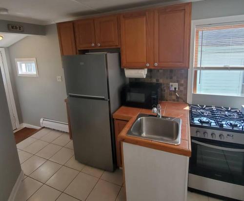 a kitchen with a stainless steel refrigerator and a sink at Beachy Bay Breeze Bungalow 2BR with parking and close to many amenities. in West Haven