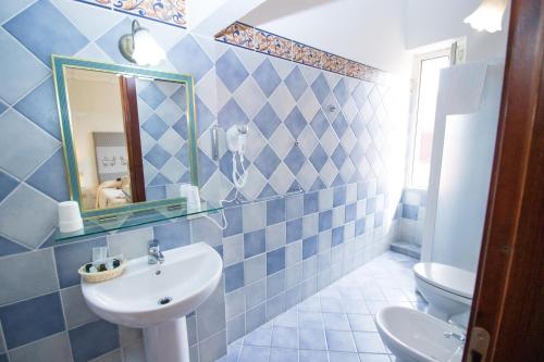 a blue and white bathroom with a sink and a mirror at Hotel Canne al Vento in Santa Teresa Gallura