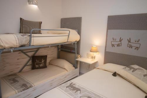 a room with two bunk beds and a table with a lamp at Hotel Canne al Vento in Santa Teresa Gallura