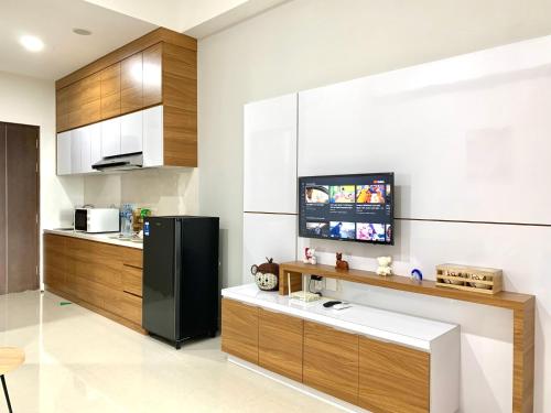 a kitchen with a black refrigerator and wooden cabinets at Family room at Apartemen Formosa Residence Nagoya Batam by Wiwi in Nagoya