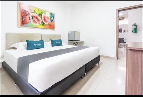 a bedroom with a large white bed with blue pillows at Hotel Millrose in Valledupar