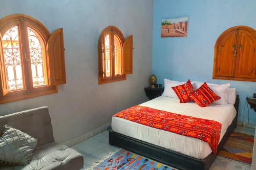een slaapkamer met een bed en 2 ramen en een stoel bij Riad ouhmidi in Marrakesh