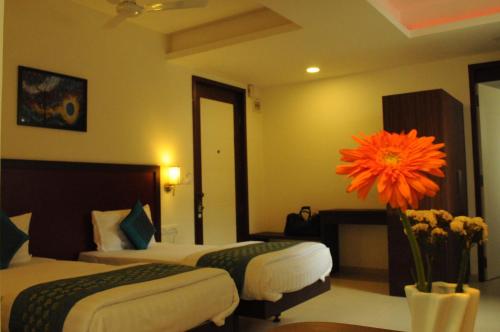 a hotel room with two beds and a flower in a vase at Ixora Suites in Bengaluru