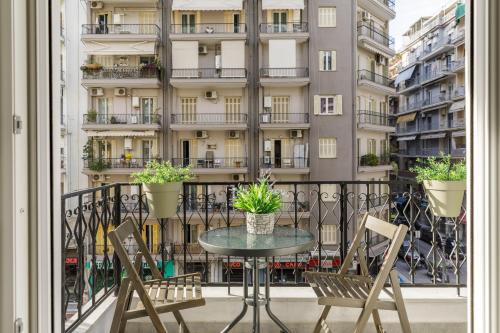 a table and chairs on a balcony with a building at NAVA Apartment in the center with private parking of stayinthess in Thessaloniki