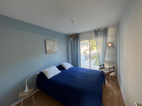 ein Schlafzimmer mit einem blauen Bett und einem Fenster in der Unterkunft Appartement face mer LA BAULE in La Baule