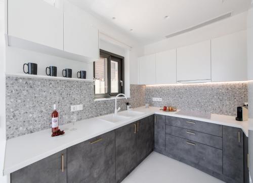 a kitchen with white counter tops and gray cabinets at Villa Anthos - Fresh modern villa, pool, close to the beach in Lefkada Town