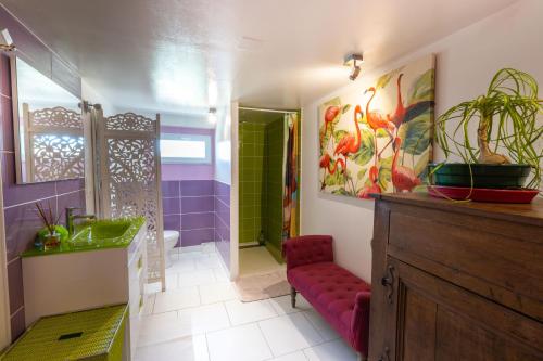 La salle de bains est pourvue de murs violets et verts ainsi que d'un tabouret rouge. dans l'établissement Le petit secret, à Saint-Aignan