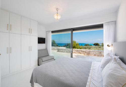 a white bedroom with a bed and a large window at Villa Anthos - Fresh modern villa, pool, close to the beach in Lefkada Town