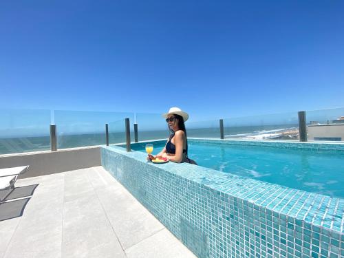 a woman sitting on the edge of a swimming pool at Pinamar Beach Resort in Pinamar